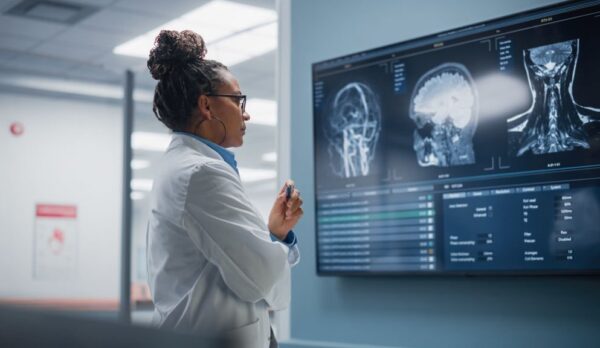 Medical Science Hospital: Confident Black Female Neurologist, Neuroscientist, Neurosurgeon, Looks at TV Screen with MRI Scan with Brain Images, Thinks about Sick Patient Treatment Method. Saving Lives