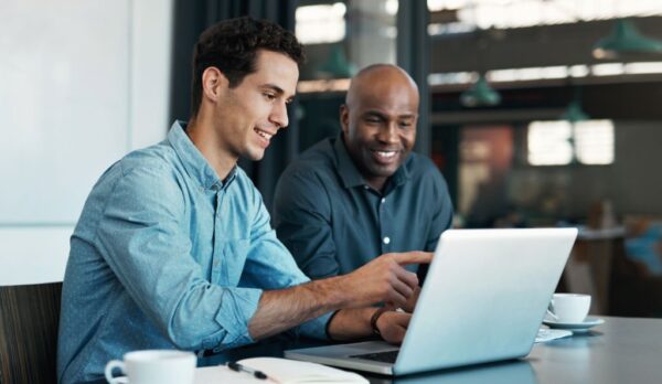 Teamwork, diversity and sales manager planning branding ideas with a creative designer on a laptop in an office. Logo, collaboration and businessman talking to an employee about a development project